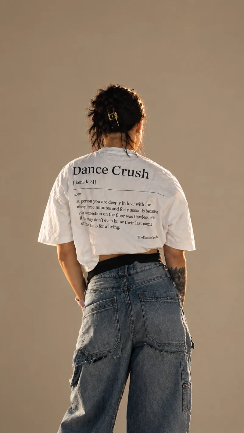 Dancer seen from behind wearing the cream “Dance Crush” T-shirt, the dictionary definition printed across the back